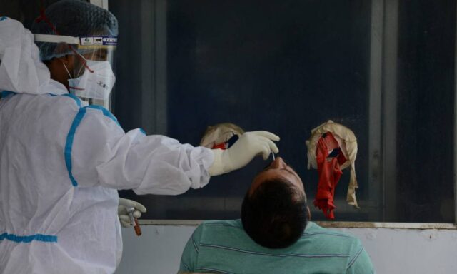 x92871598_A-health-worker-collects-nasal-swab-for-a-Covid-19-coronavirus-RT-PCR-test-at-the-North-Ben.jpg.pagespeed.ic.hVwkq0UtIj