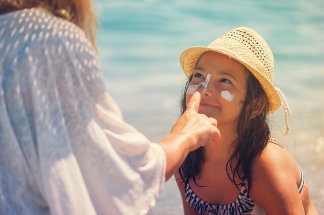 Young Mother Applying Suntan Lotion On Daughter's Face