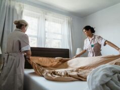 women putting bed sheet in a bed
