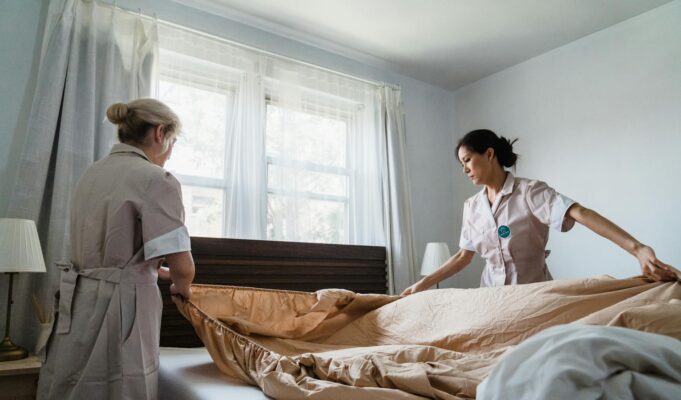 women putting bed sheet in a bed