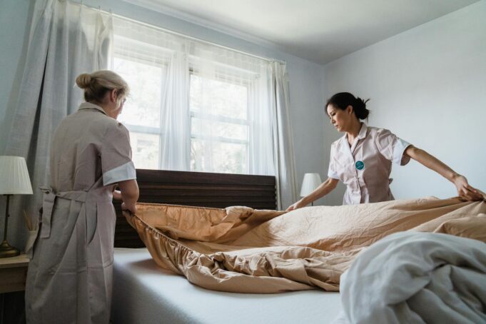 women putting bed sheet in a bed